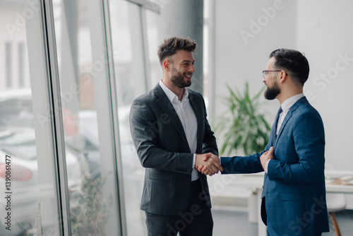 Foto Two businessmen shaking hands in modern office, closing a business deal