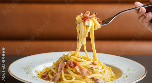 Delicious spaghetti carbonara with bacon and creamy sauce on white plate