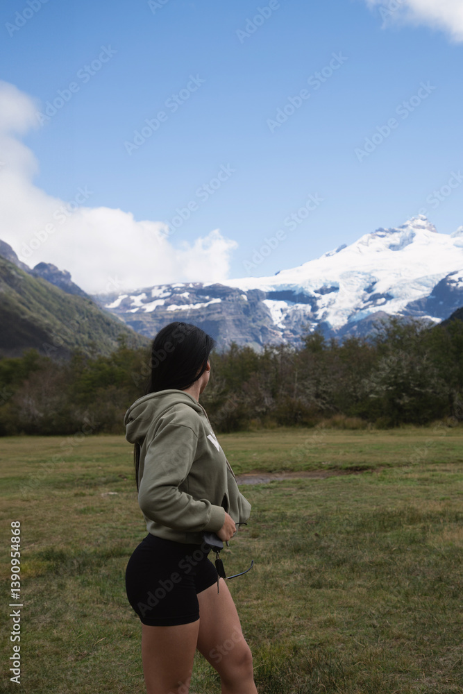 Fototapeta premium brunette long hair woman training in the hills looking back in mountain landscape with green hoodie and black sports shorts