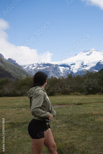 brunette long hair woman training in the hills looking back in mountain landscape with green hoodie and black sports shorts