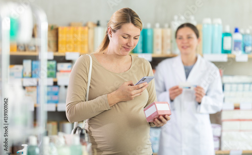 Pregnant woman scanning qr code for box of pills with woman pharmacist in pharmacy