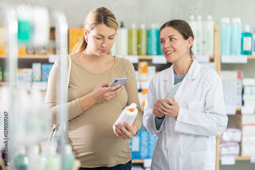 Obraz na płótnie Pregnant woman in pharmacy scans QR code on antifungal cream product, checks certificate on manufacturers website. Girl pharmacist offer similar product w salonie