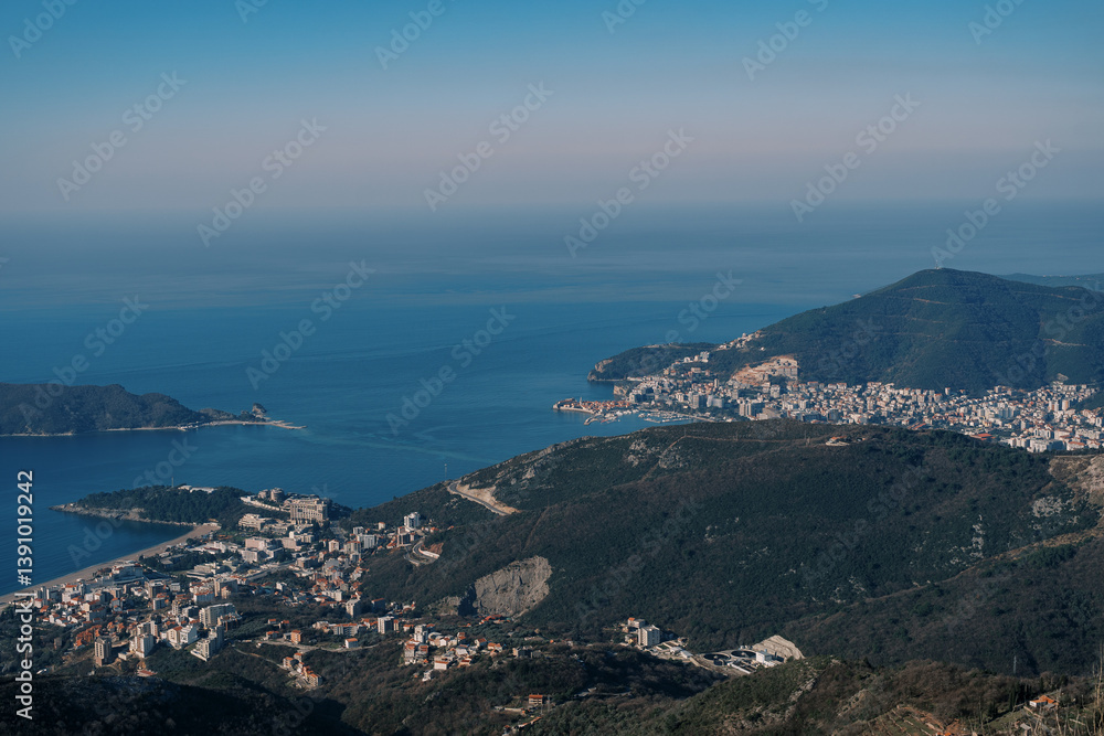 View from the top of the mountain to the settlements at the foot of the mountains on the seashore against the blue sky View from the top of the mountain to the settlements at the foot of the mountains on the seashore against the blue sky