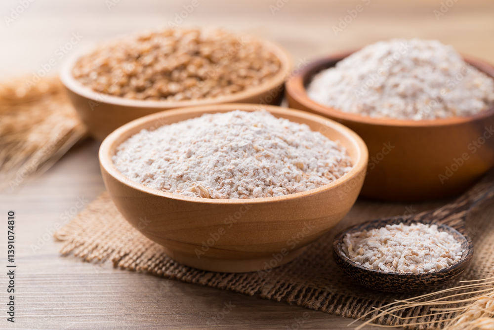 Whole wheat flour with wheat grain in bowl on wooden background Whole wheat flour with wheat grain in bowl on wooden background