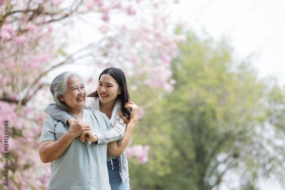 A young woman lovingly embraces an elderly woman from behind as they smile together under blooming pink trees. This joyful moment captures the warmth and bond of family in a serene spring setting. A young woman lovingly embraces an elderly woman from behind as they smile together under blooming pink trees. This joyful moment captures the warmth and bond of family in a serene spring setting.