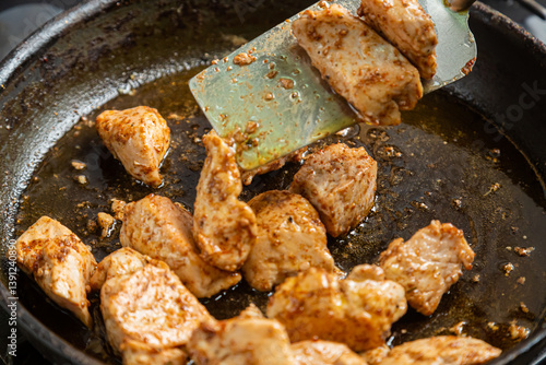 Obraz na plátně Chicken fillet pieces are fried in a frying pan in spices and turned over
