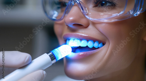 woman is undergoing teeth whitening procedure in dental clinic, showcasing bright white teeth and smile. dental professional uses blue light device for effective treatment