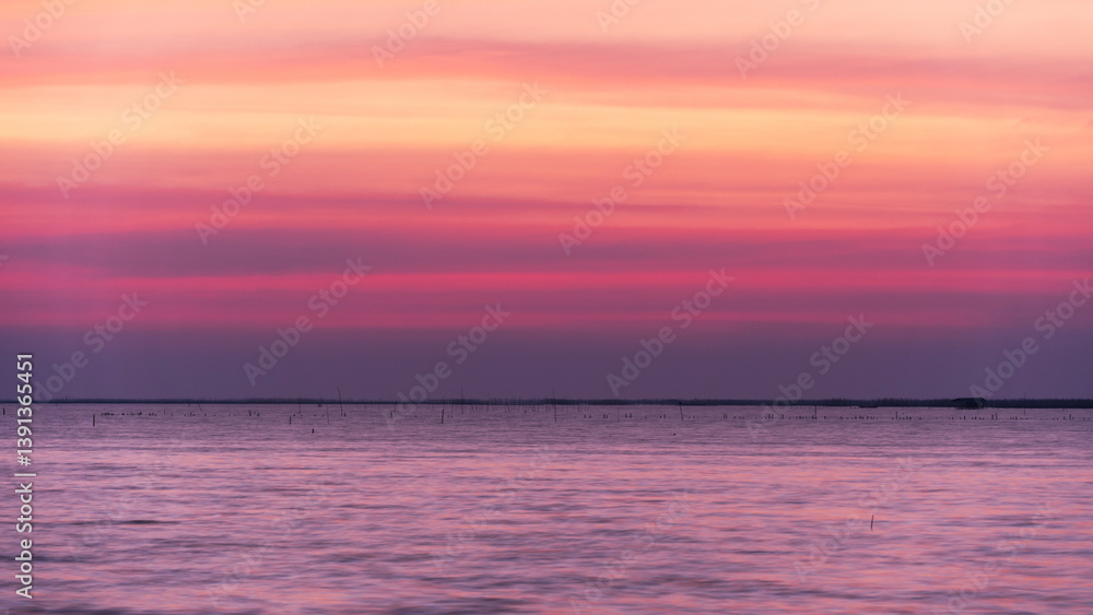 Fototapeta premium Beautiful sunrise or sunset over the sea, with colorful sky, soft clouds, and gentle waves.