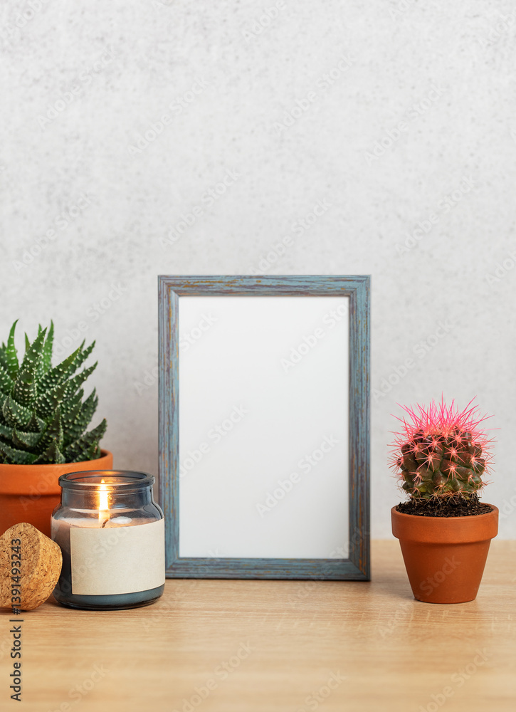 Empty frame, burning candle and succulents creating cozy home atmosphere