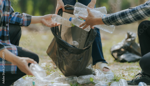 Tableau sur toile Volunteers collect plastic bottles, put trash in black trash bags to clean the park, avoid pollution, be environmentally friendly and ecologically friendly