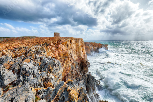 Obraz na płótnie Attractive view of cliffs in valley Cala Domestica with old tower and storm on the sea w salonie