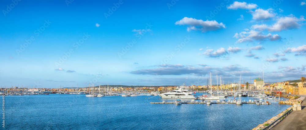 Unbelivable summer view of the Alghero Marina yacht port at the Gulf of Alghero with anchored sailboats.