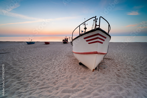 Fototapeta Naklejka Na Ścianę i Meble -  Fishing boat on the beach at sunset. Baltic Sea, seaside town of Dąbki. Polish coast. 