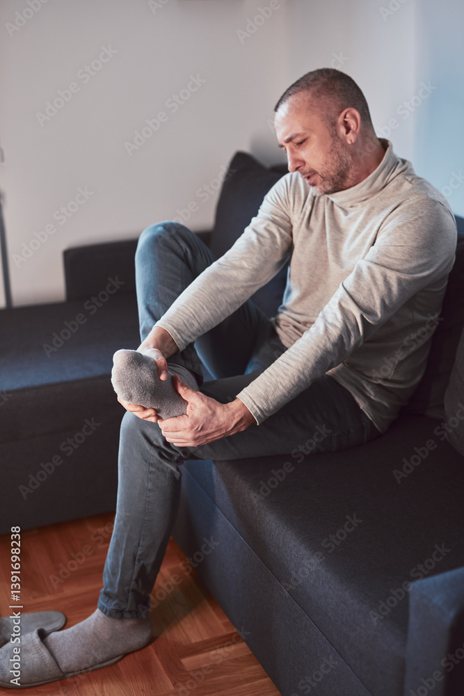 Man with ankle and foot pain at home.