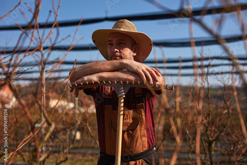 Obraz na płótnie Male gardener with hat working with a rake in a blueberries organic farm. w salonie