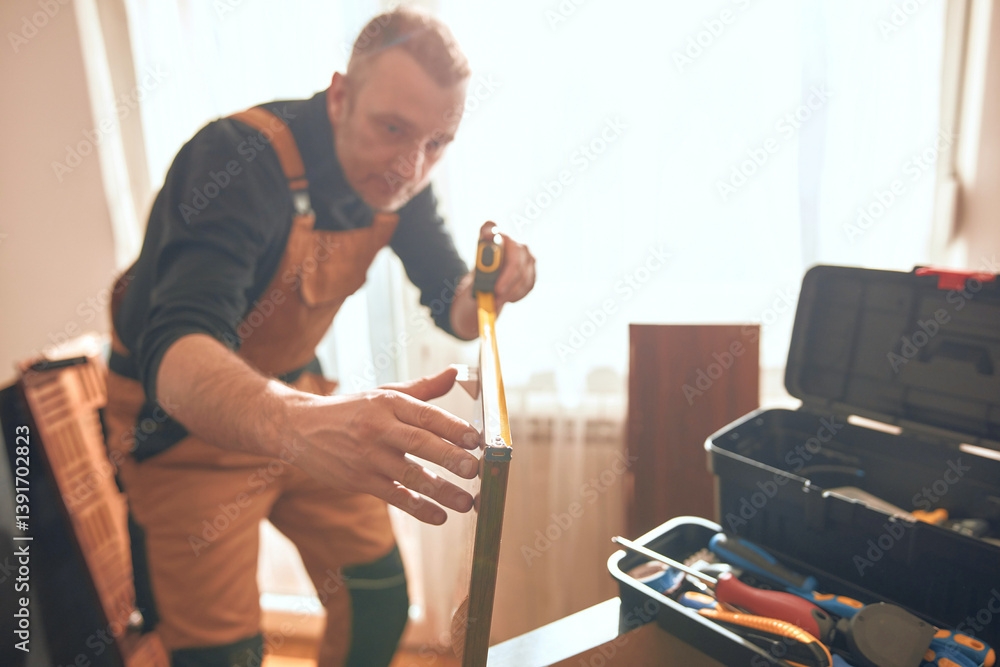 Carpenter working and assembling furniture in a new apartment.