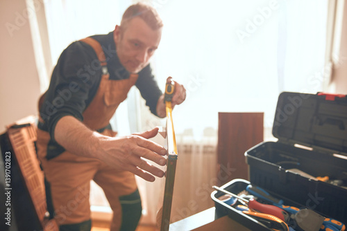 Obraz na płótnie Carpenter working and assembling furniture in a new apartment. w salonie