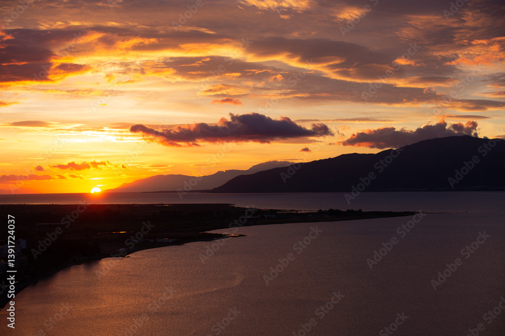 Obraz premium Sunset Over Coastal City and Sea in Greece