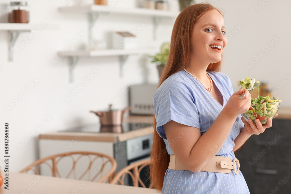 Young woman eating vegetable salad in kitchen
