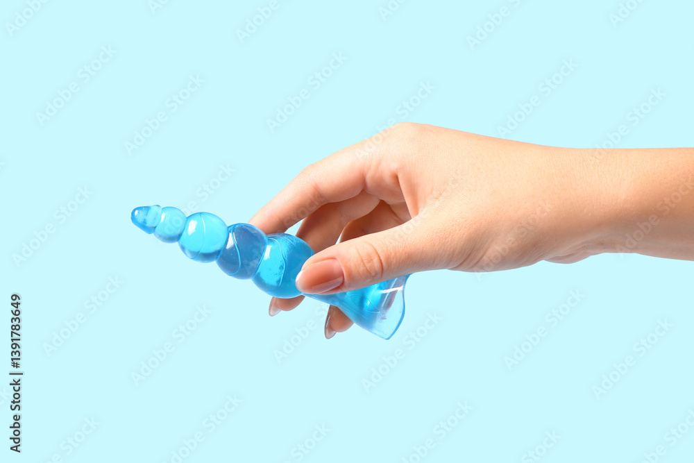 Female hand with anal plug on blue background Female hand with anal plug on blue background