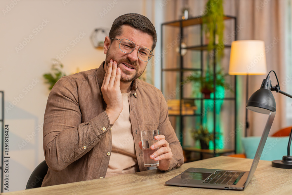 Caucasian young businessman freelancer sitting at home office table drinking cold water feeling toothache touching mouth, painful expression of dental illness, gum disease, dental disease concepts. Caucasian young businessman freelancer sitting at home office table drinking cold water feeling toothache touching mouth, painful expression of dental illness, gum disease, dental disease concepts.
