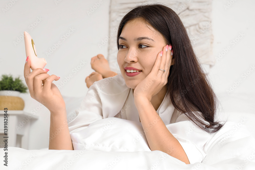 Beautiful young woman with vibrator lying on bed Beautiful young woman with vibrator lying on bed