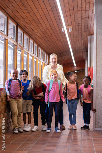 Obraz na płótnie Female teacher with diverse group of school children standing in hallway, smiling together w salonie