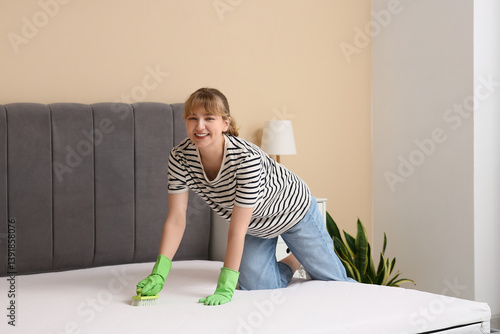 Young woman cleaning mattre...