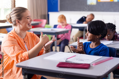 Using sign language, female teacher and boy engaging in communication at school