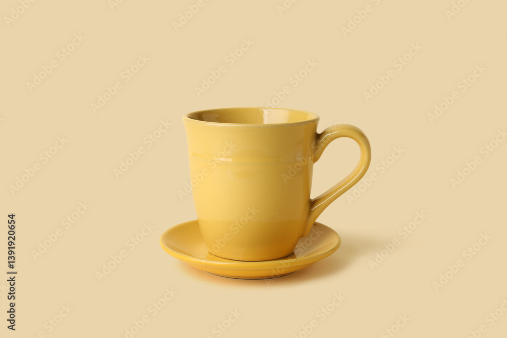 Yellow ceramic empty mug with saucer on beige background Yellow ceramic empty mug with saucer on beige background