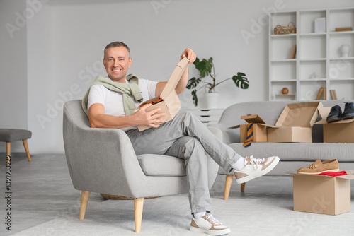 Mature man unpacking box wi...