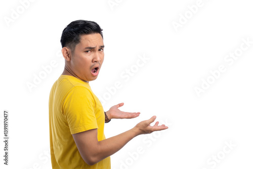 Foto Shocked young Asian man looking confused while raising his hands and turning his