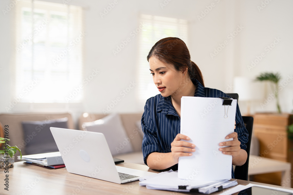 Busy working amidst stacks of paper files, searching and checking for unfinished documents among the folders and papers on home office desk Busy working amidst stacks of paper files, searching and checking for unfinished documents among the folders and papers on home office desk