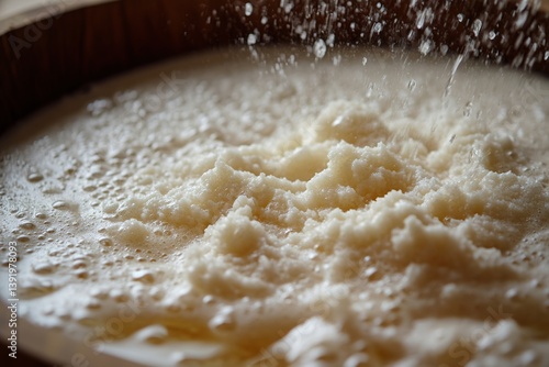 A close-up of sattu being mixed in water, creating a thick, frothy texture in a wooden bowl.