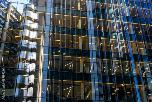 Glass curtain walls of office towers with warm interior lighting, suggesting activity, enterprise and collaboration.