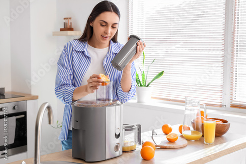 Young woman making orange j...