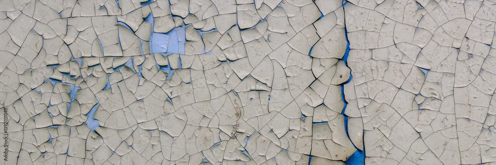 Peeling paint on the wall. Panorama of a concrete wall with old cracked flaking paint. Weathered rough painted surface with patterns of cracks and peeling. Panoramic texture for background and design.