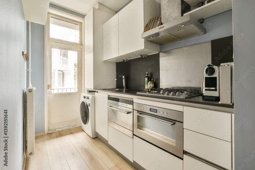Fototapeta premium A modern kitchen featuring sleek cabinetry, various appliances, and a spacious layout bathed in natural light from the window.