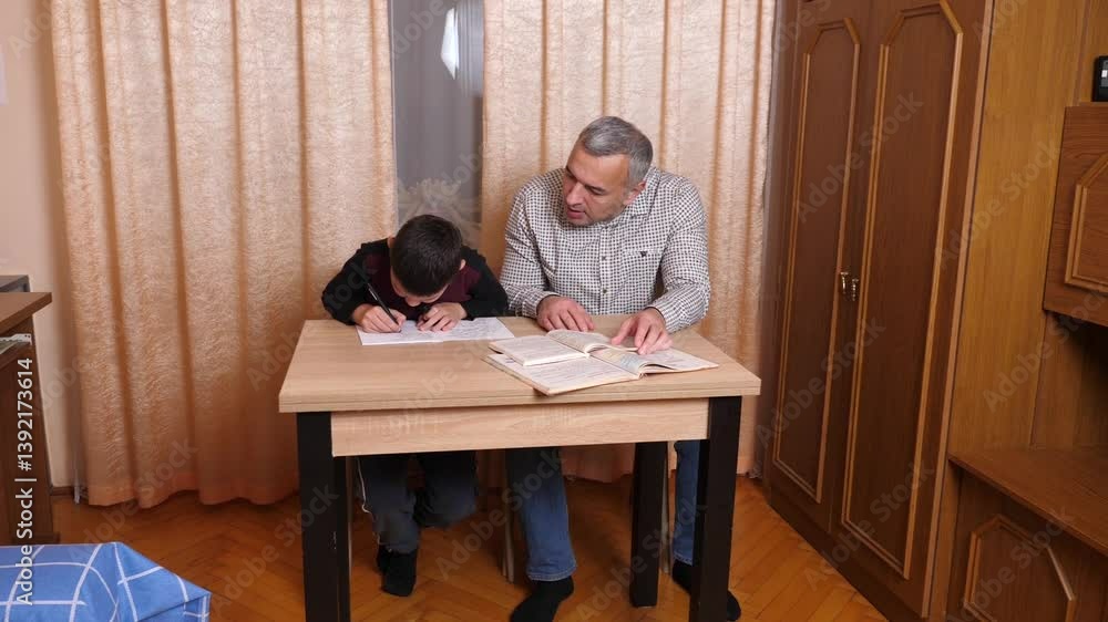 Father helping his son with homework. Home education concept. Father helping his son with homework. Home education concept.