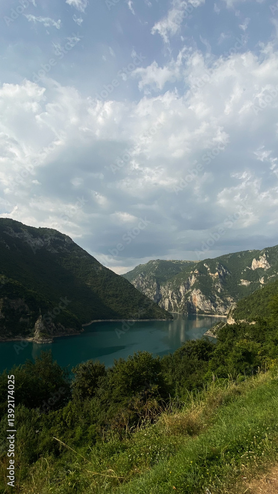 Fototapeta premium Scenic view of a lake surrounded by mountains under a cloudy sky