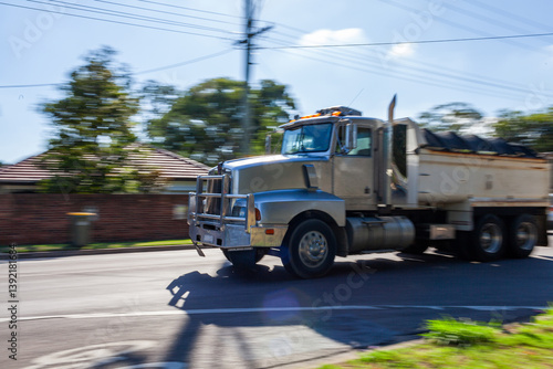 Panning shot of truck traveling along highway through town with motion blurred background