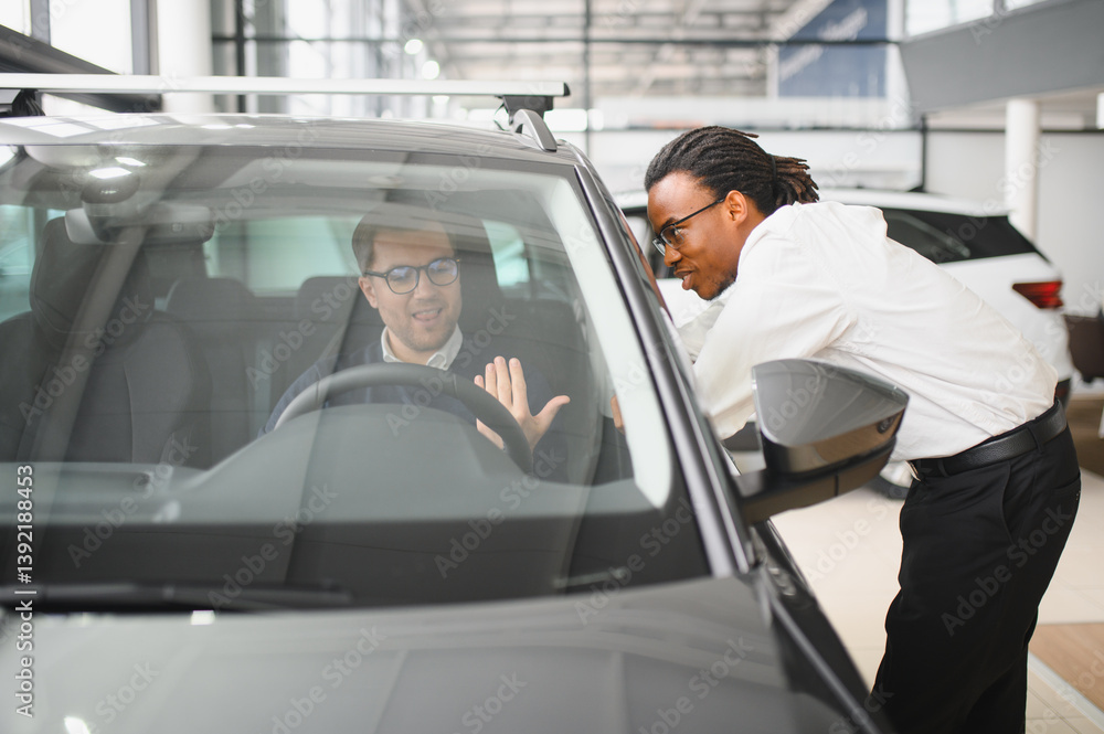 A consultant at a car dealership helps a customer choose a new car A consultant at a car dealership helps a customer choose a new car