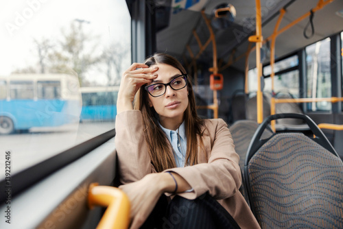 Worried young woman sitting in public bus and getting nervous during ride.