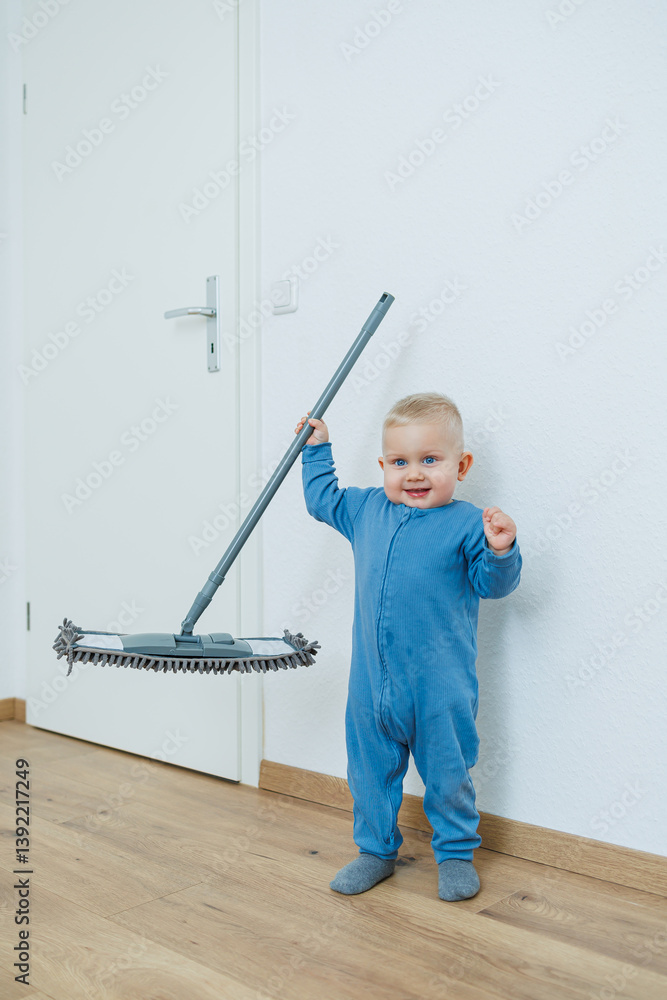 Little boy helper cleaning at home. Blond toddler boy washes the floor with a mop, helping his mother clean at home, free space. Child learns to clean the house.