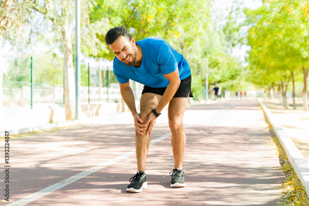 Runner suffering knee pain during outdoor workout on running track