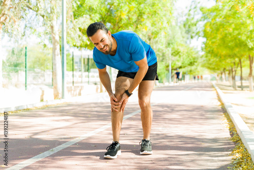 Obraz na płótnie Runner suffering knee pain during outdoor workout on running track w salonie