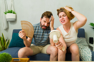 Portrait of a couple sweating and suffering from summer heat wave at home