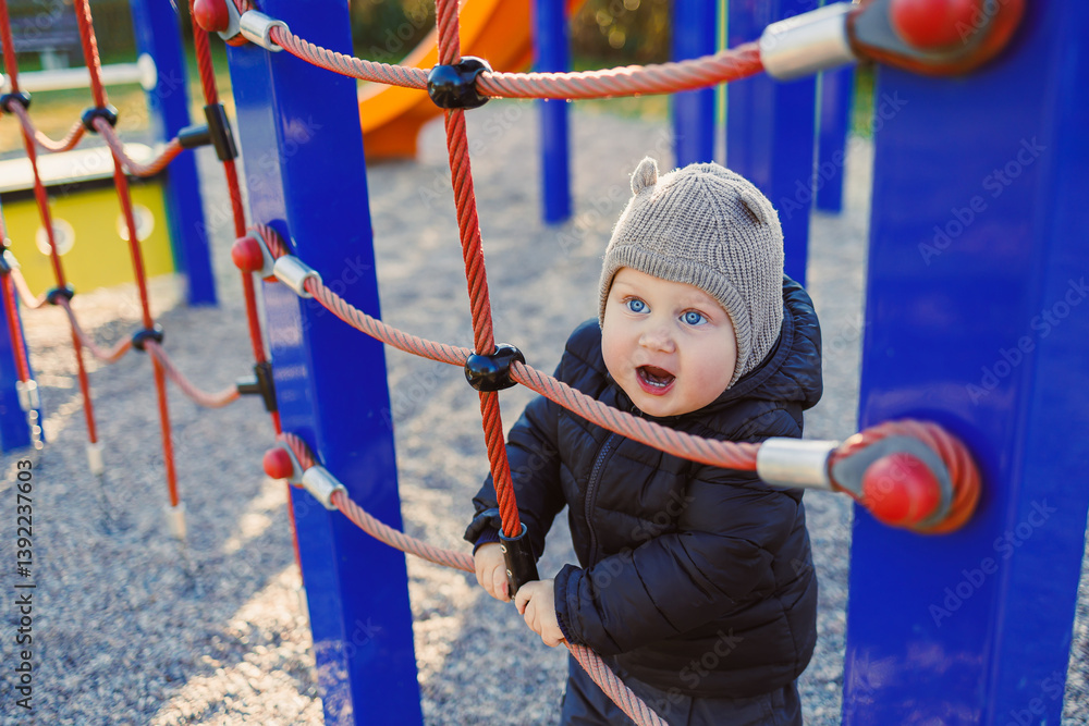 Child walking outdoors. Happy toddler boy on a walk on the playground. Child development, healthy lifestyle of the child. Boy outdoors on an autumn walk. Cheerful boy in the city park.