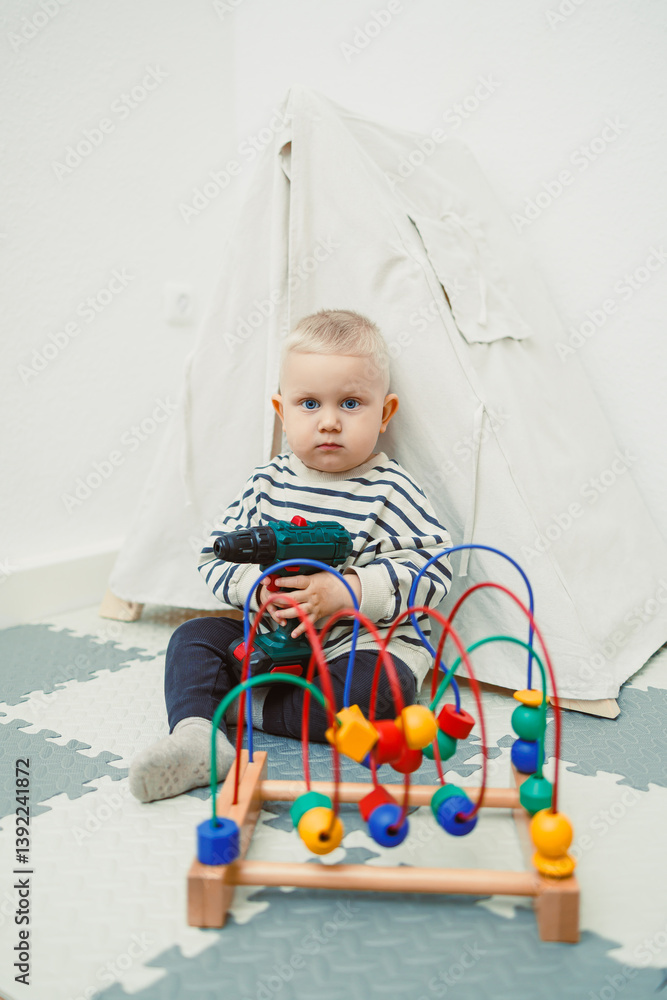 Toys for little children. Toddler boy playing with educational toy. Child playing with toy beads in kindergarten or nursery. Toddler child in nursery.