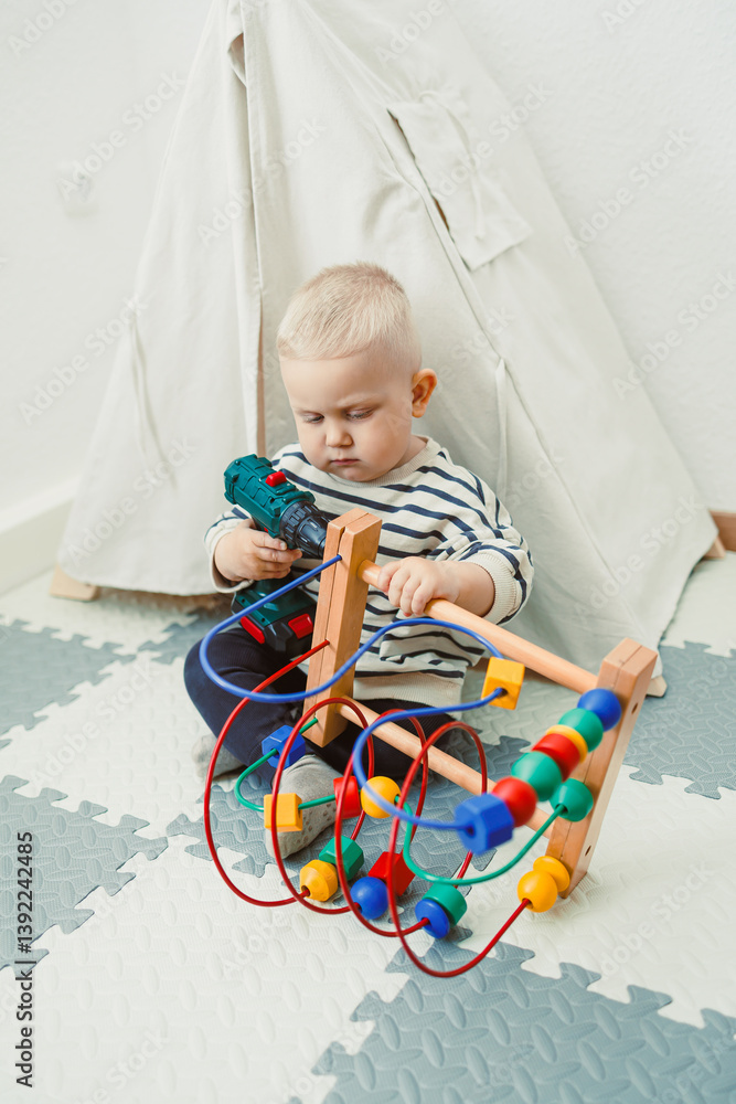 Toys for little children. Toddler boy playing with educational toy. Child playing with toy beads in kindergarten or nursery. Toddler child in nursery.